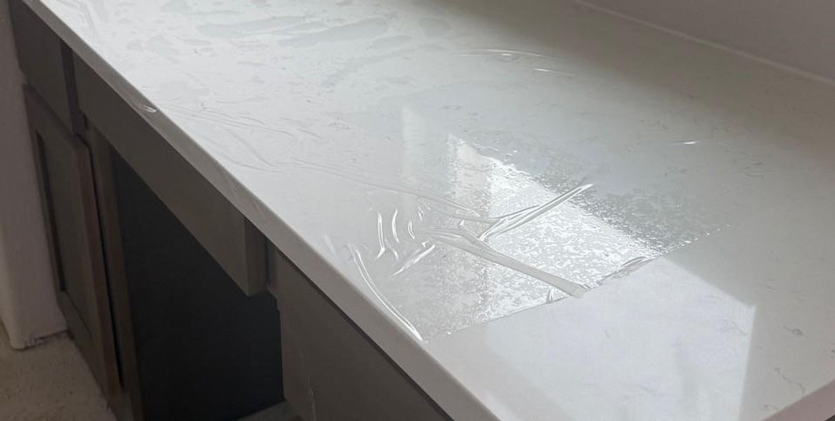 White countertop with subtle veining, paired with built-in cabinetry featuring dark wood-finish doors and a lighter wood-finish frame White countertop with subtle veining, paired with built-in cabinetry featuring dark wood-finish doors and a lighter wood-finish frame