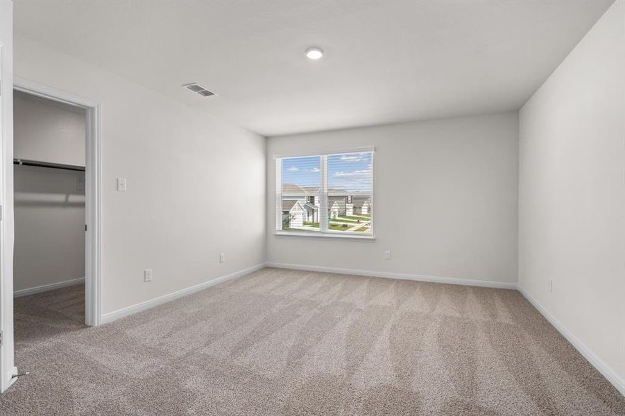 Unfurnished bedroom with a spacious closet and light carpet