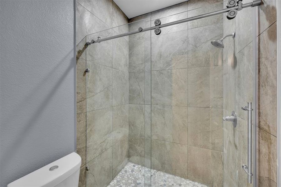 Full bath featuring a textured wall and a shower stall