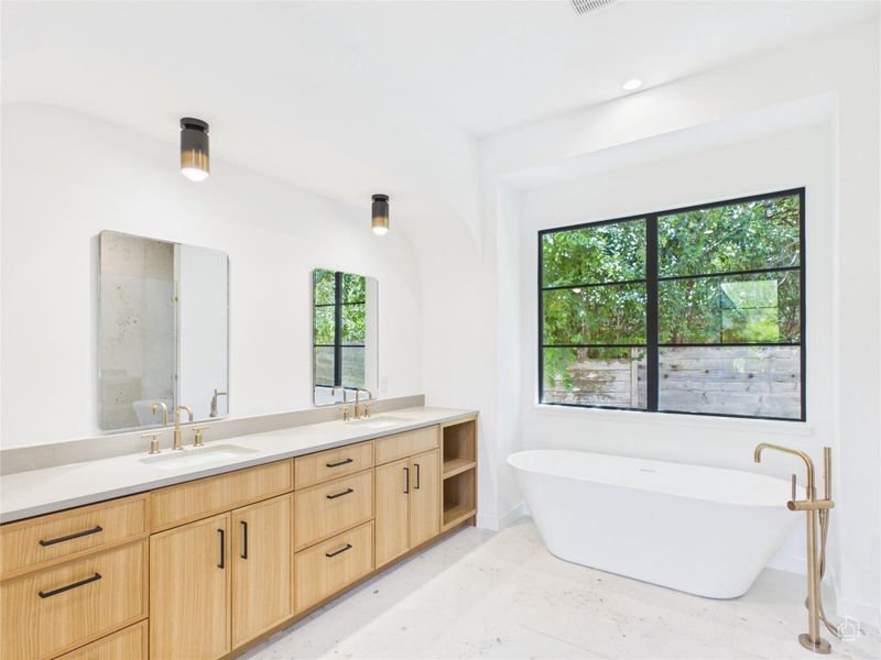 Natural wood cabinetry and a freestanding tub define this serene retreat with large window views.