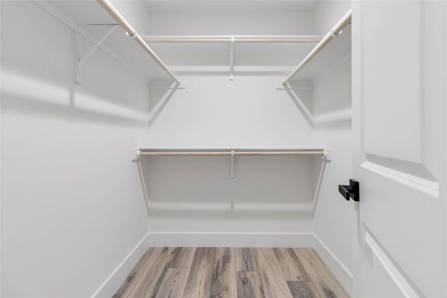Walk-in closet in the primary bedroom featuring ample shelving for abundant storage space. Walk-in closet in the primary bedroom featuring ample shelving for abundant storage space.