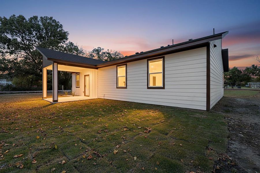 Back of property at dusk featuring a patio and a yard Back of property at dusk featuring a patio and a yard