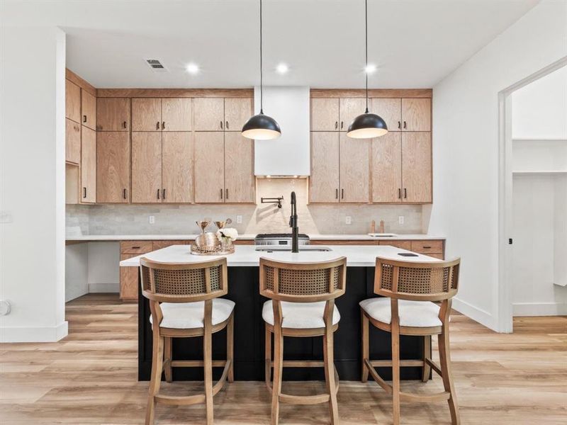 Kitchen featuring pendant lighting, a kitchen breakfast bar, tasteful backsplash, light wood-style floors, and recessed lighting