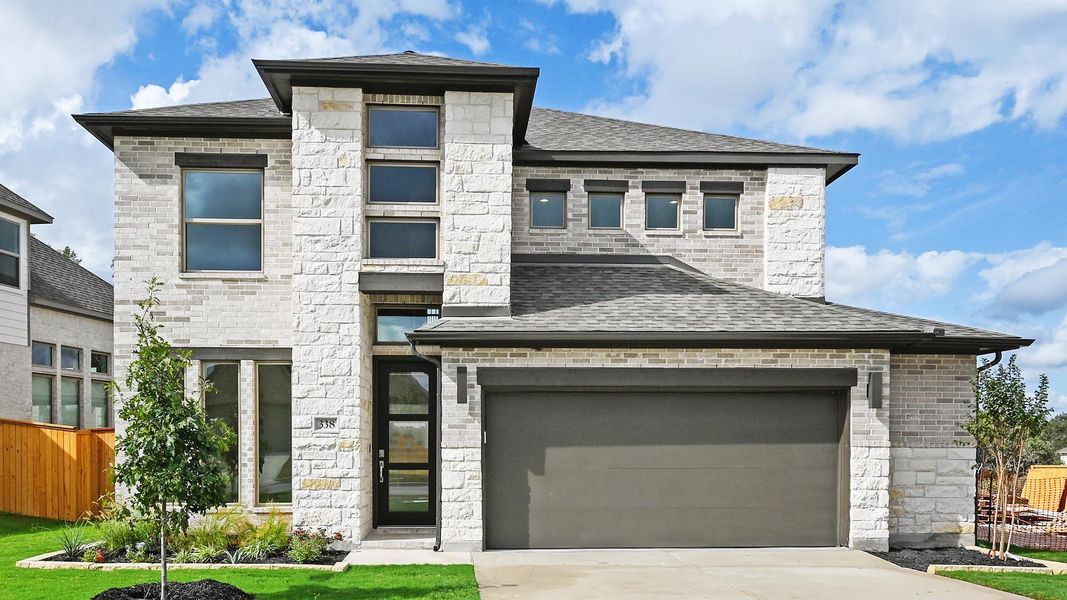 View of front of property with stone siding, driveway, and a garage