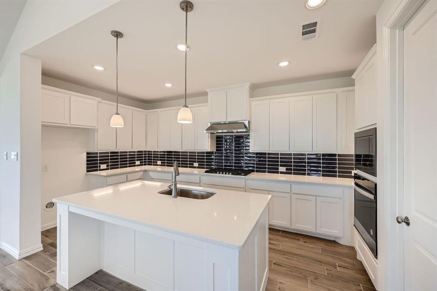 Kitchen featuring sink, an island with sink, light hardwood / wood-style floors, white cabinets, and exhaust hood