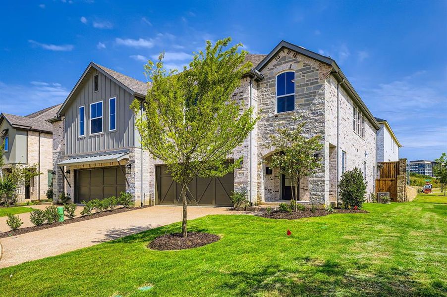 View of front of house featuring board and batten siding, an attached garage, driveway, and a front yard