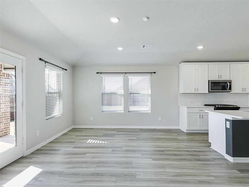 Kitchen with light wood-type flooring, white cabinetry, and backsplash