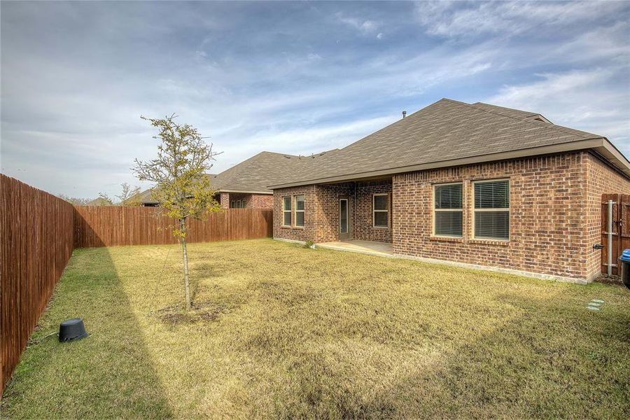 Rear view of property featuring roof with shingles, a fenced backyard, a patio area, and brick siding
