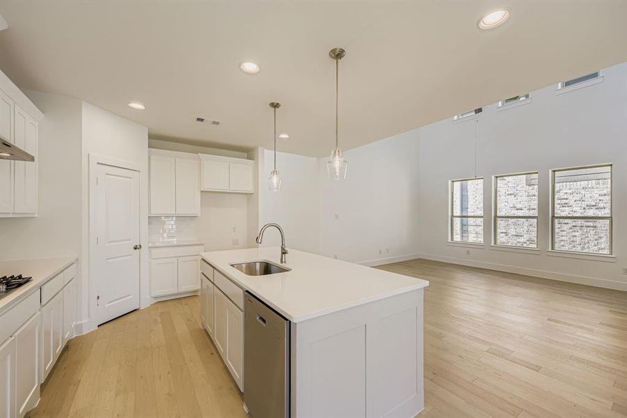 Kitchen featuring recessed lighting, white cabinetry, pendant lighting, light wood-type flooring, and an island with sink Kitchen featuring recessed lighting, white cabinetry, pendant lighting, light wood-type flooring, and an island with sink