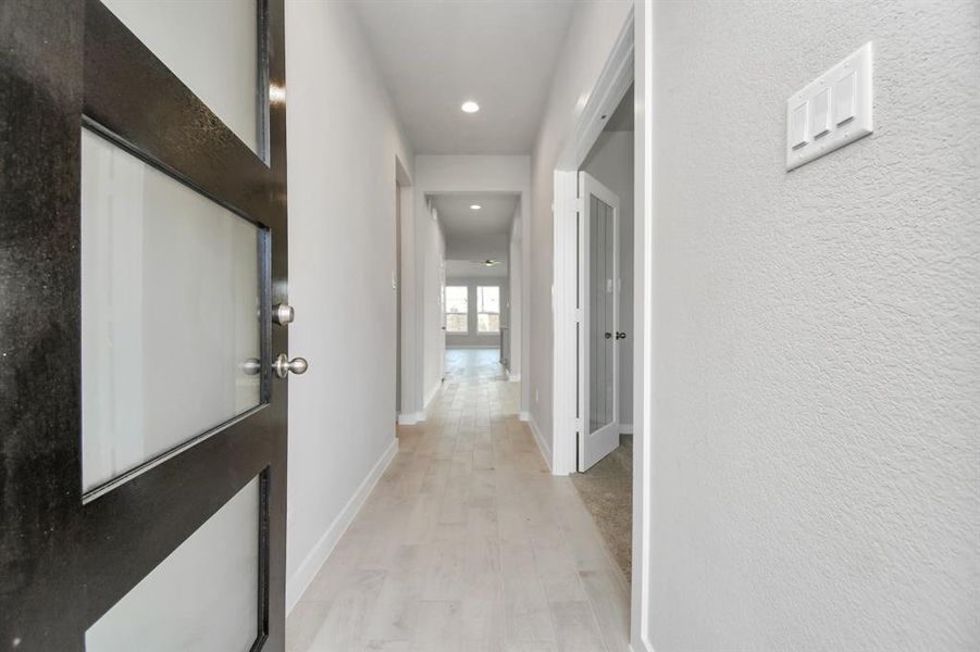 The grand entrance beckons with its soaring ceilings, adorned with elegant wood-look tile flooring featuring sleek oversized baseboards.