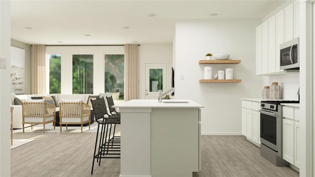 Kitchen featuring appliances with stainless steel finishes, an island with sink, sink, white cabinets, and a kitchen breakfast bar