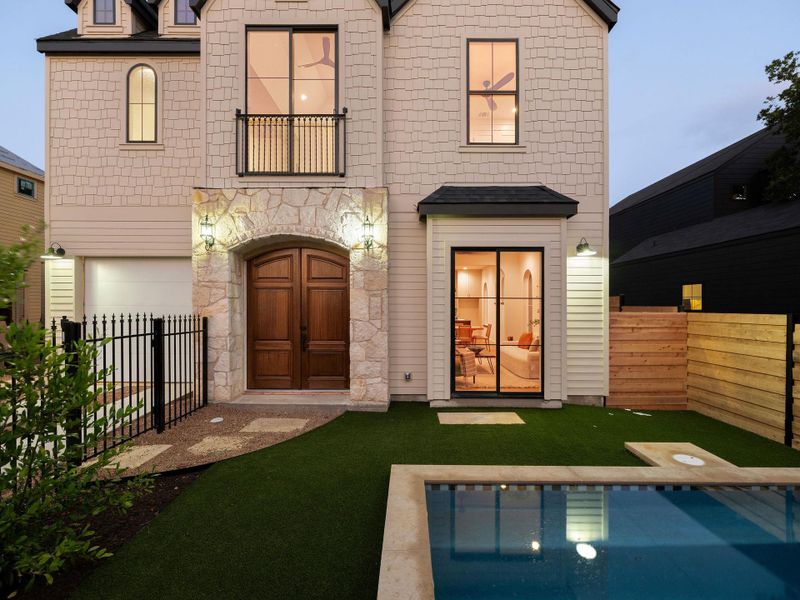 Elegant wooden double doors set within a stone archway welcome you to this charming residence with a private pool.