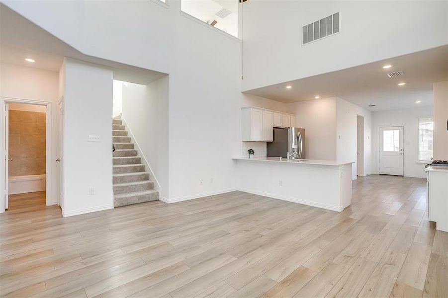 Unfurnished living room featuring a high ceiling and light wood-type flooring