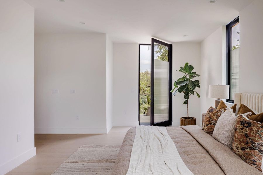Bedroom featuring a wall of windows, access to outside, and light wood-style flooring Bedroom featuring a wall of windows, access to outside, and light wood-style flooring