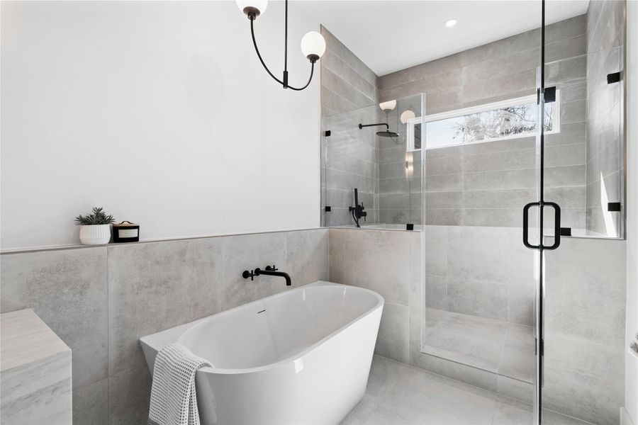 Unwind in style with a deep soaking tub, streamlined black hardware, and a spacious glass-enclosed shower, all framed by calming, spa-like finishes.