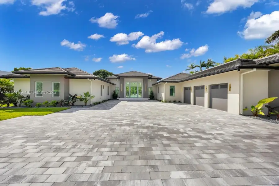 Single-story estate featuring a multi-car garage, a paver driveway, light-toned exterior finish, and a covered entryway