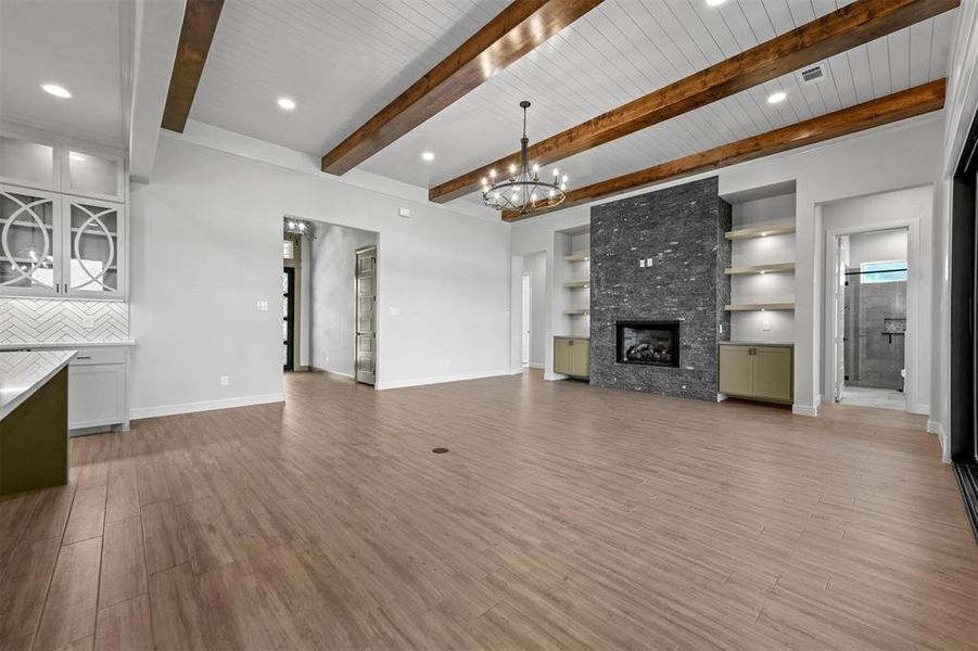 Unfurnished living room featuring beam ceiling, wooden ceiling, built in features, a fireplace, and light wood-type flooring