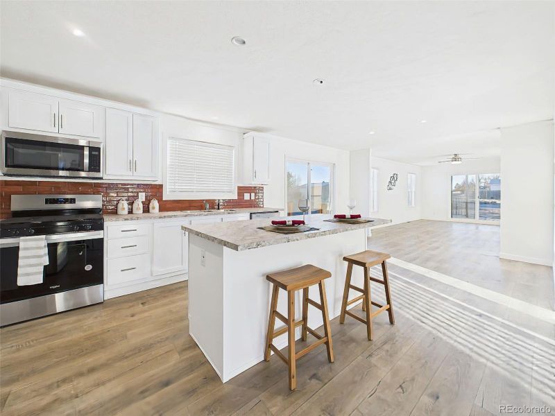 A functional layout featuring a central island with bar seating, stainless steel appliances, and panoramic flow into surrounding living zones—ideal for entertaining or family gatherings.