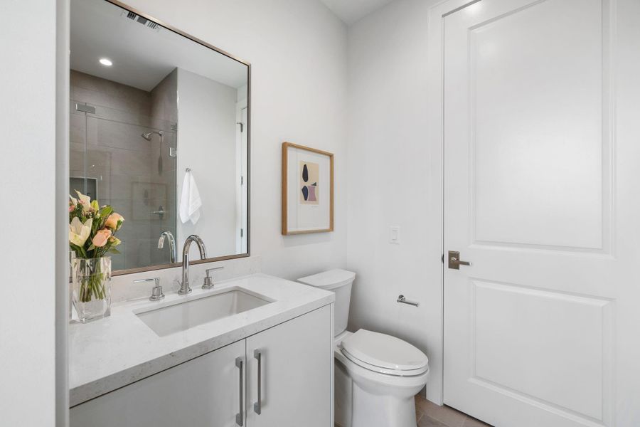 En-suite guest bathroom features a frameless glass shower and closet.