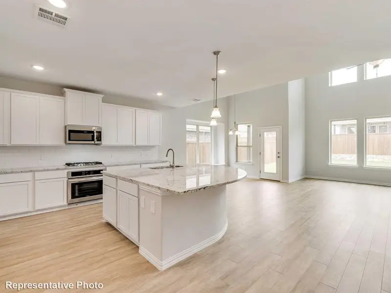 The kitchen features white cabinetry, stainless steel appliances, and a central island with a granite countertop and sink