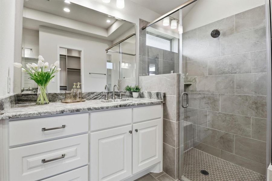 Close-up of the vanity/sink areas and shower. Beautiful tile work in the shower.