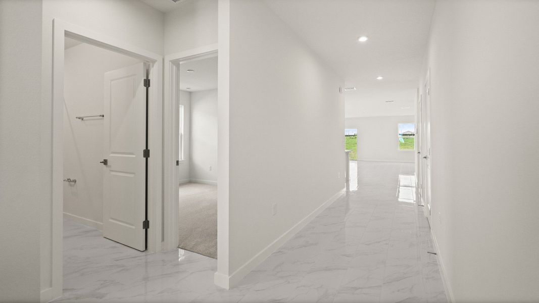 Hallway with sleek tile floors and open sightlines to the main living space in the Castaway Model by DRB Homes