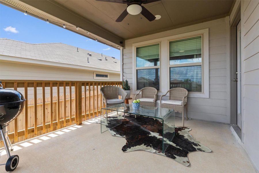 Covered patio featuring a ceiling fan with integrated lighting, concrete flooring, and a wooden railing Covered patio featuring a ceiling fan with integrated lighting, concrete flooring, and a wooden railing