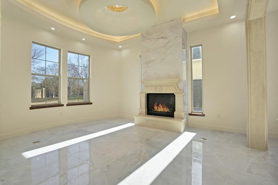 Unfurnished living room with a tray ceiling and a premium fireplace