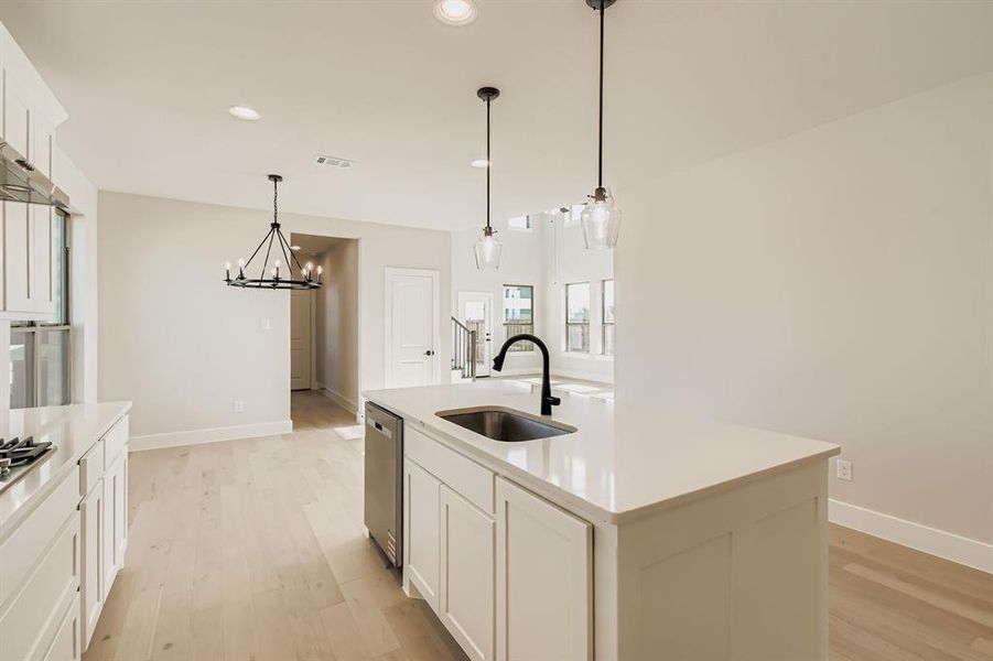 Kitchen featuring light wood-style flooring, a chandelier, a kitchen island with sink, recessed lighting, and decorative light fixtures