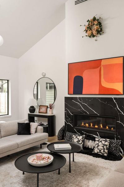 A stylish living area features a linear fireplace set within a black marble surround, complemented by vaulted ceilings and elegant hard surface flooring. A stylish living area features a linear fireplace set within a black marble surround, complemented by vaulted ceilings and elegant hard surface flooring.
