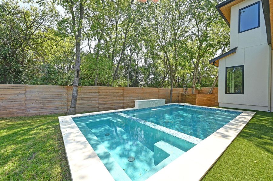 View of swimming pool with a pool with connected hot tub, a fenced backyard, a patio, and view of scattered trees