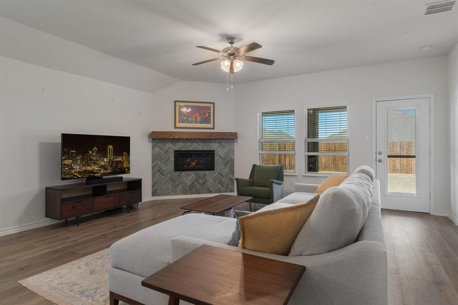 Living room with baseboards, visible vents, wood finished floors, vaulted ceiling, and a fireplace