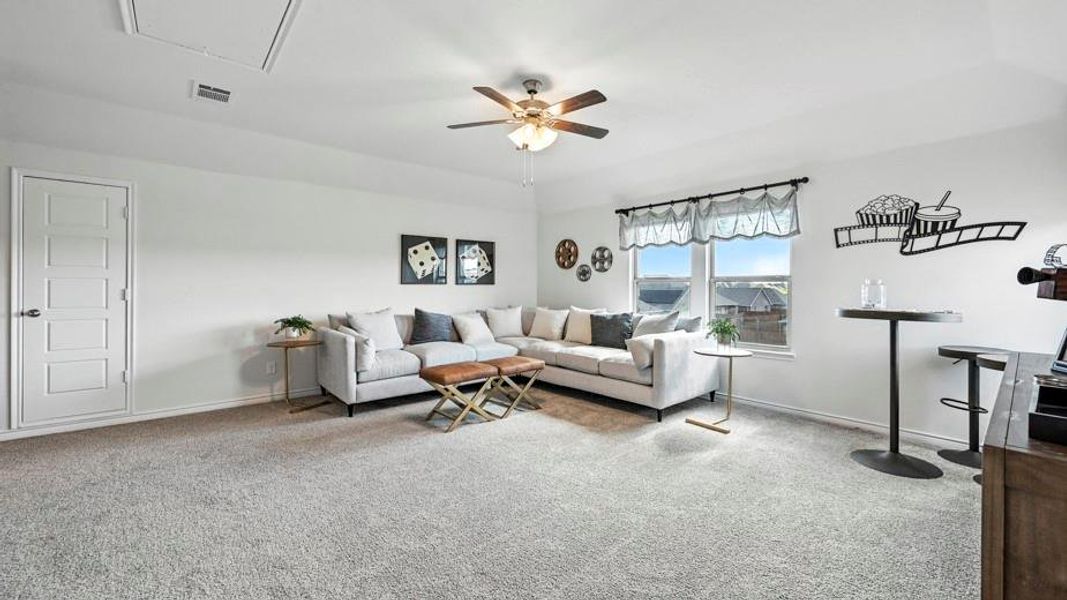 Spacious recreation area featuring plush carpeting, a multi-pane window, and a ceiling fan with integrated lighting