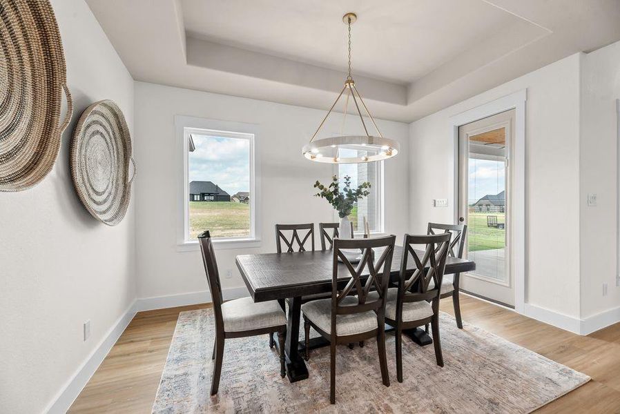 Dining room featuring a tray ceiling and light wood-style floors Dining room featuring a tray ceiling and light wood-style floors
