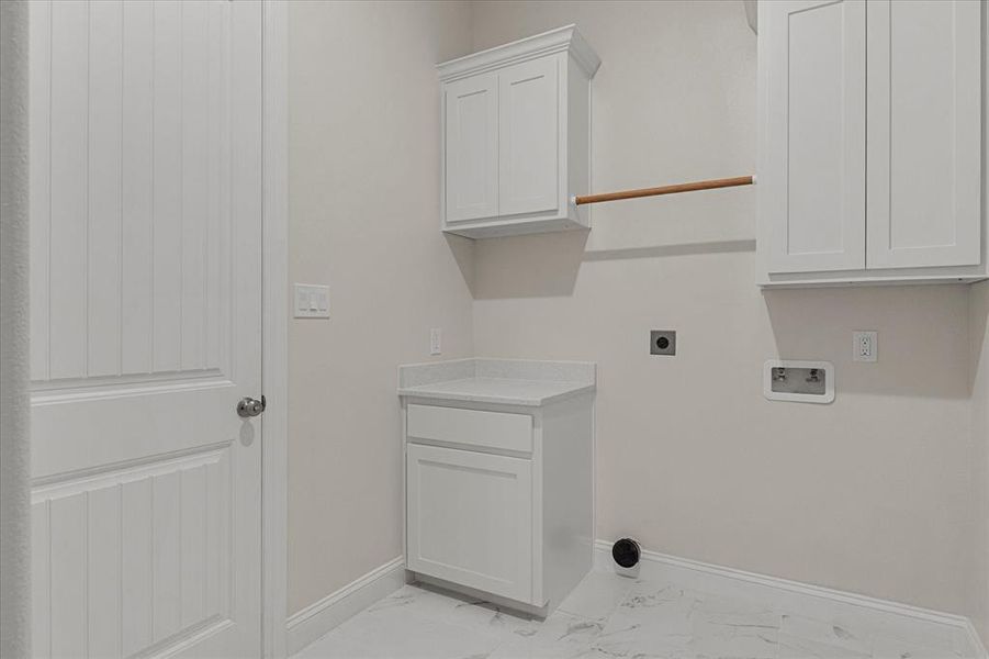 Laundry area featuring light marble finish flooring, electric dryer hookup, washer hookup, and cabinet space