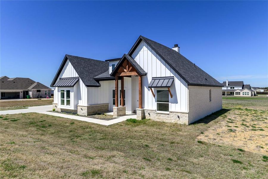 Modern farmhouse featuring board and batten siding, a chimney, a front lawn, a standing seam roof, and a shingled roof Modern farmhouse featuring board and batten siding, a chimney, a front lawn, a standing seam roof, and a shingled roof