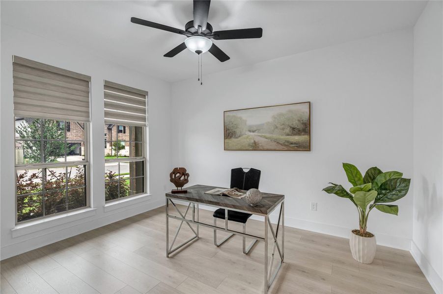 Well-lit office with light-toned hardwood flooring and a contemporary ceiling fan.