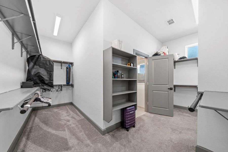Oversized walk-in closet offering exceptional storage with dual hanging areas, built-in shelving, and ample space for organization—designed to accommodate an extensive wardrobe with ease.