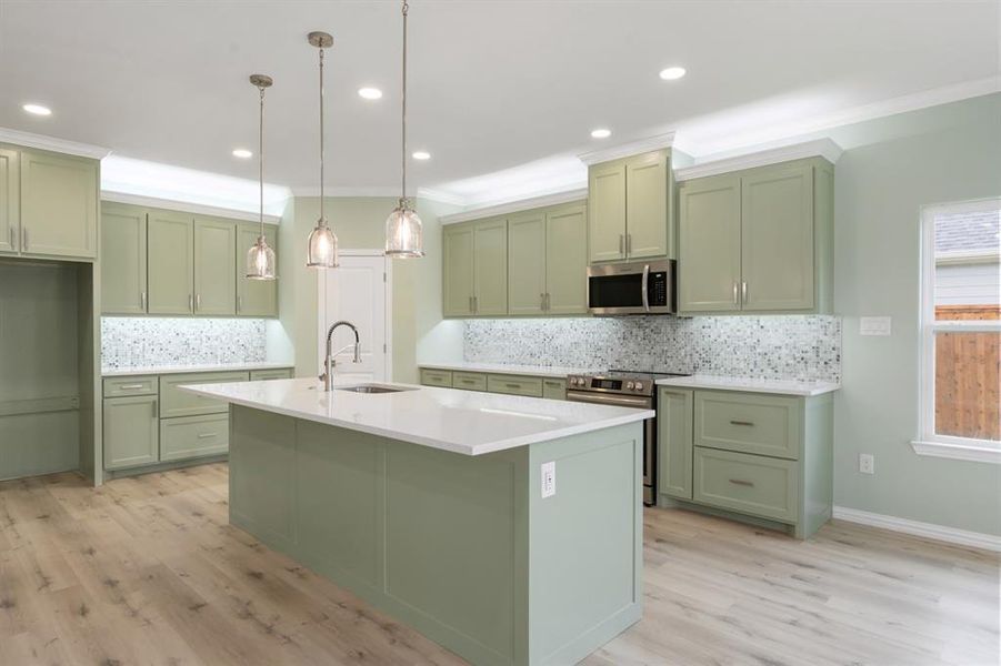 Kitchen featuring stainless steel appliances, backsplash, and a center island with sink