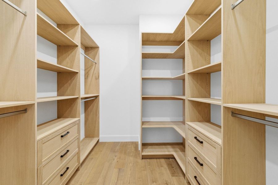 Walk in closet with light wood-type flooring plus built in cabinetry