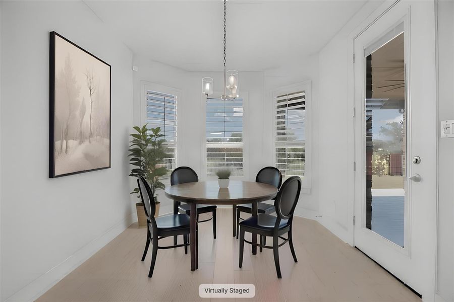 A well-lit breakfast area offers light wood flooring and a view of the outdoors through bay windows.