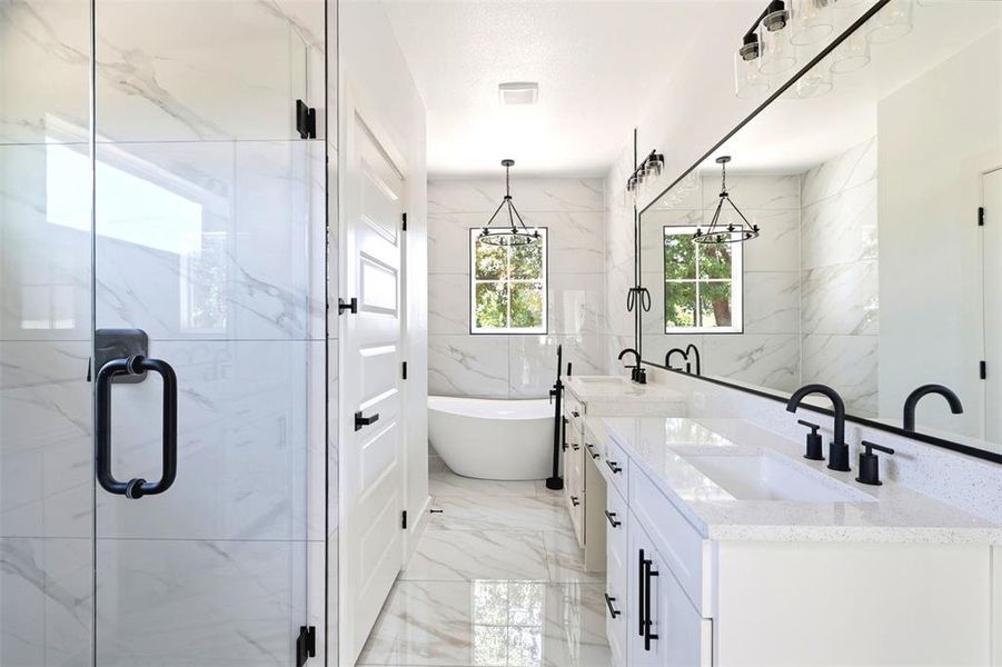 Modern bathroom featuring a frameless glass shower enclosure, a dual vanity with quartz countertops, matte black hardware, and a freestanding soaking tub