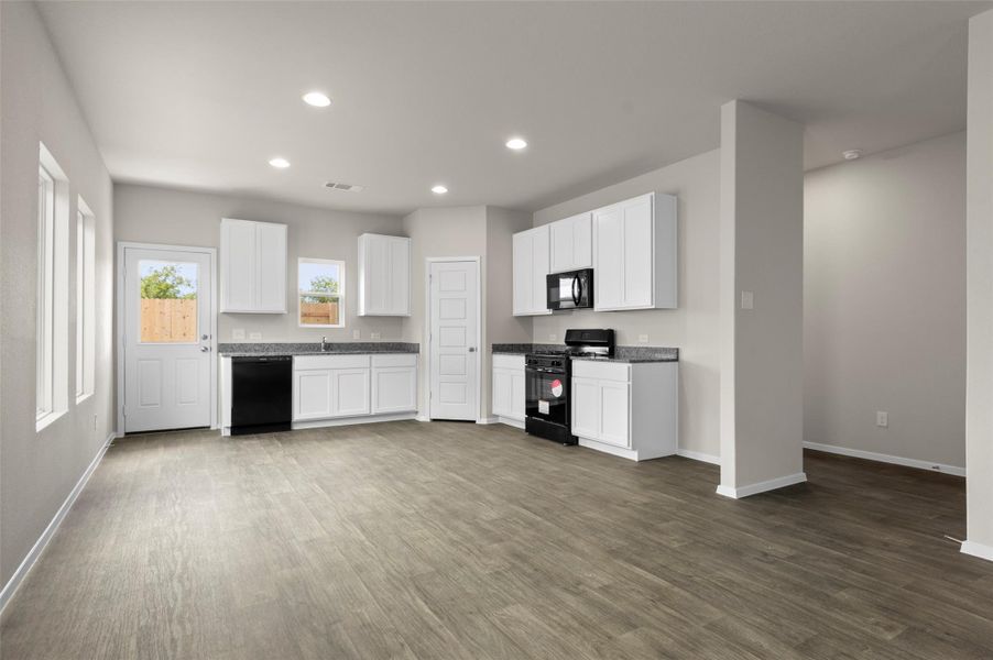 Kitchen with black appliances, recessed lighting, dark wood finished floors, white cabinets, and dark countertops Kitchen with black appliances, recessed lighting, dark wood finished floors, white cabinets, and dark countertops