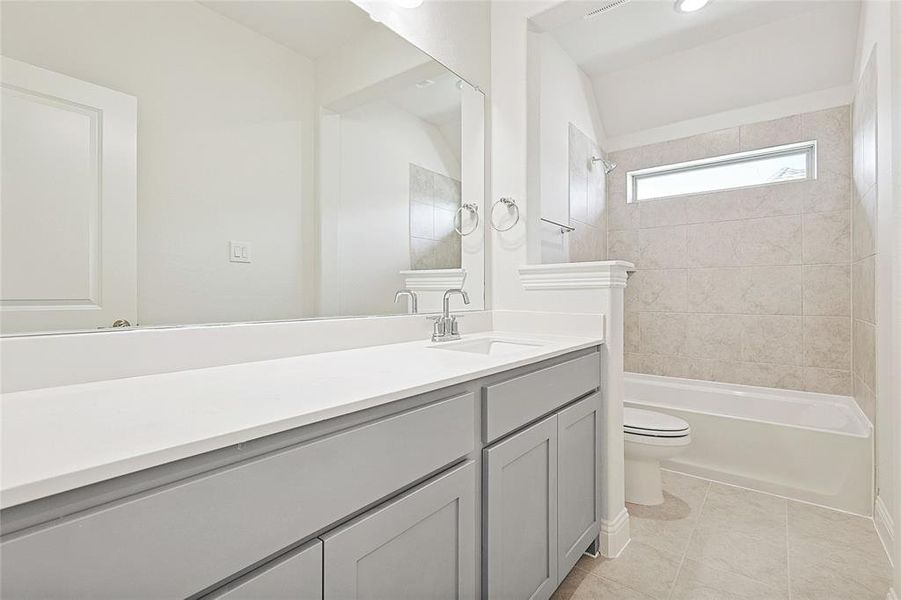 Full bathroom with vanity, tiled shower / bath combo, toilet, and tile patterned floors