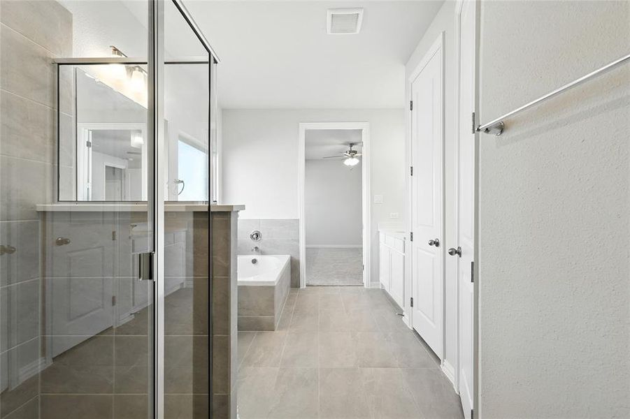 Full bathroom featuring a shower stall, a garden tub, light tile patterned floors, ceiling fan, and vanity Full bathroom featuring a shower stall, a garden tub, light tile patterned floors, ceiling fan, and vanity