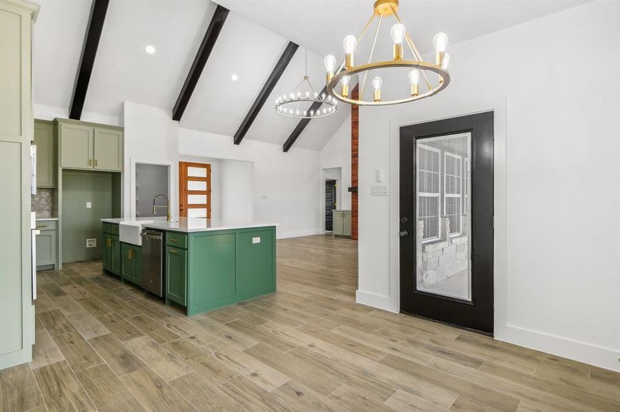 Kitchen with green cabinets, a kitchen island with sink, decorative light fixtures, beam ceiling, and light wood-type flooring Kitchen with green cabinets, a kitchen island with sink, decorative light fixtures, beam ceiling, and light wood-type flooring