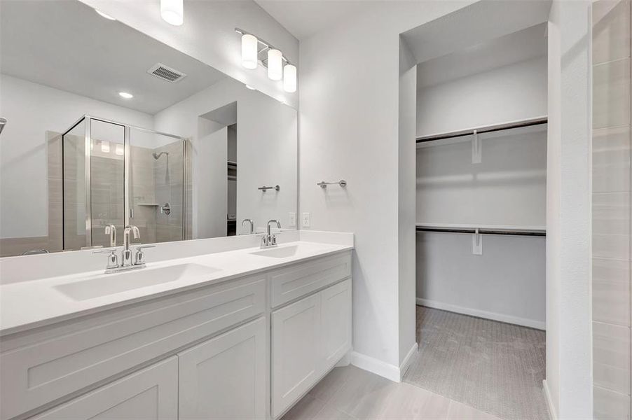 Dual vanity with white cabinetry and integrated sinks, complemented by a large wall mirror and contemporary overhead lighting