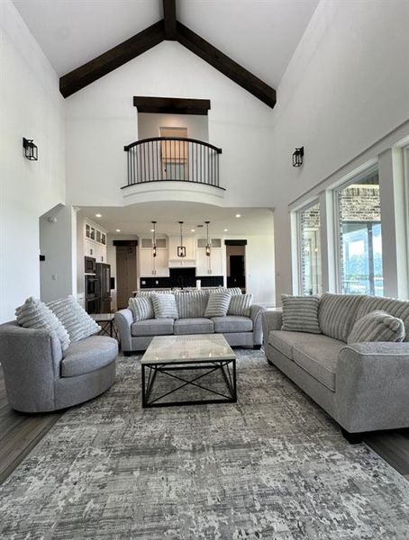 Living area featuring high vaulted ceiling, wood finished floors, and beam ceiling Living area featuring high vaulted ceiling, wood finished floors, and beam ceiling