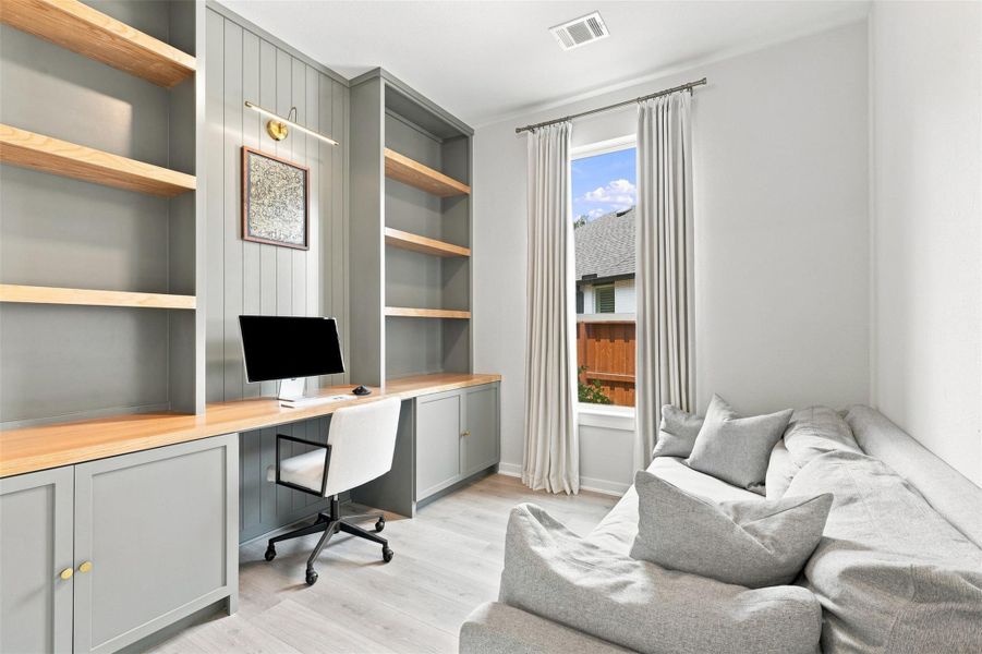 Home Office on first floor. Custom built in desk with white oak shelves. Outlets located inside cabinets to store printer etc. Custom window treatment