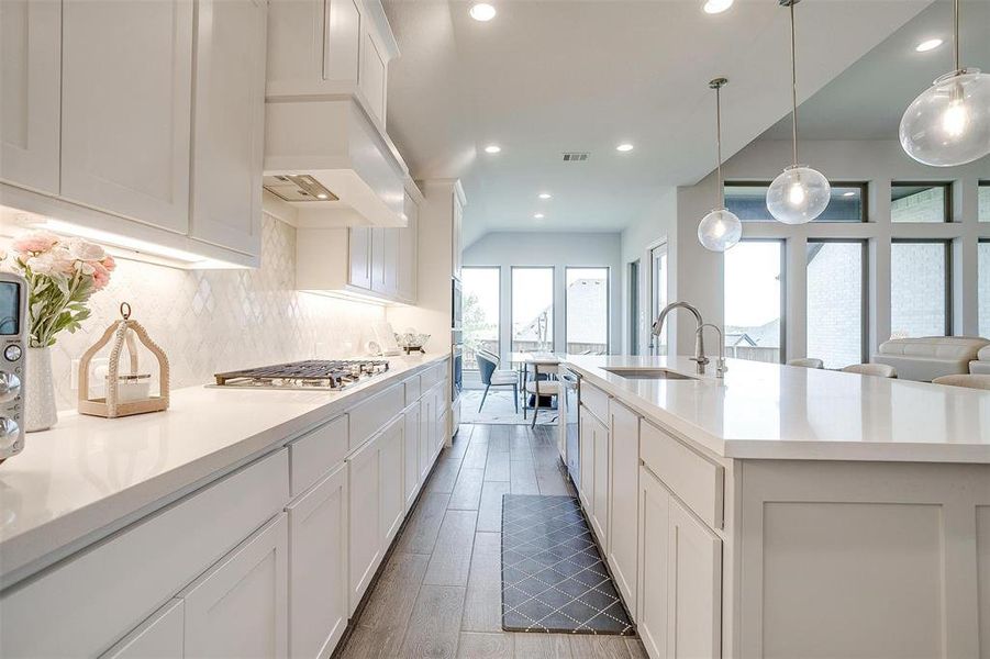 Kitchen with a sink, stainless steel gas cooktop, decorative backsplash, white cabinets, and recessed lighting Kitchen with a sink, stainless steel gas cooktop, decorative backsplash, white cabinets, and recessed lighting